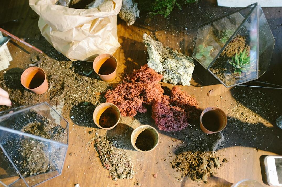 Terracotta pots, bag of potting soil and perlite on a table