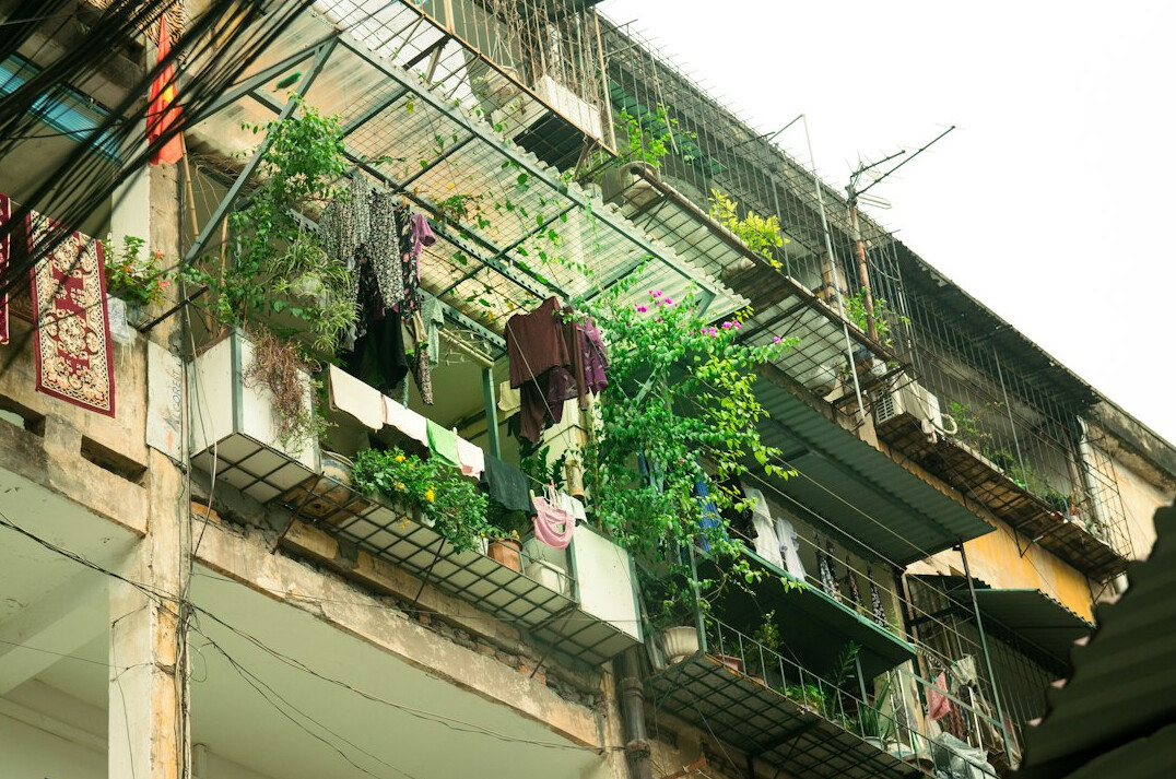 Narrow apartment balcony with vertical planters and hanging pots